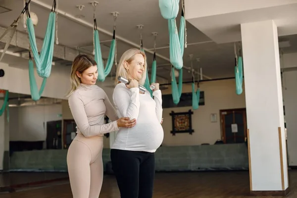 Trainer helping pregnant woman to do excercises with a dumbbells — Fotografie, imagine de stoc