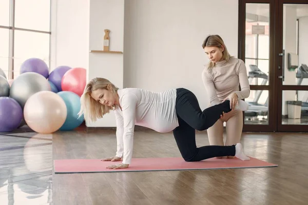 Eğitmen hamile bir kadının yoga yapmasına yardım ediyor. — Stok fotoğraf