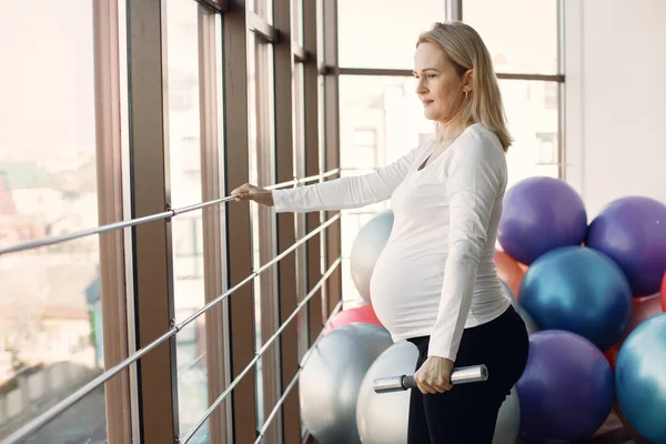 Pregnant woman doing fitness excercise in bright fitness studio — Fotografie, imagine de stoc