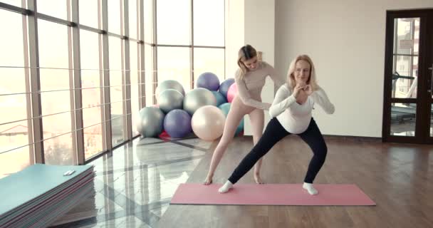Zwangere vrouw en haar personal trainer doen stretching oefeningen — Stockvideo