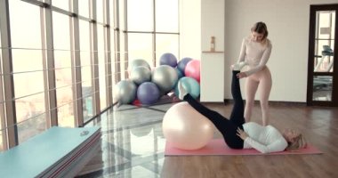 Hamile kadın ve kişisel antrenörü esneme egzersizleri yapıyor.