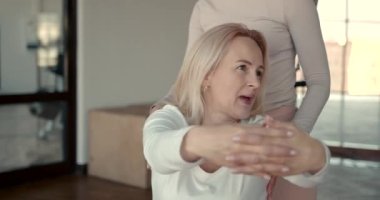 Hamile kadın ve kişisel antrenörü esneme egzersizleri yapıyor.