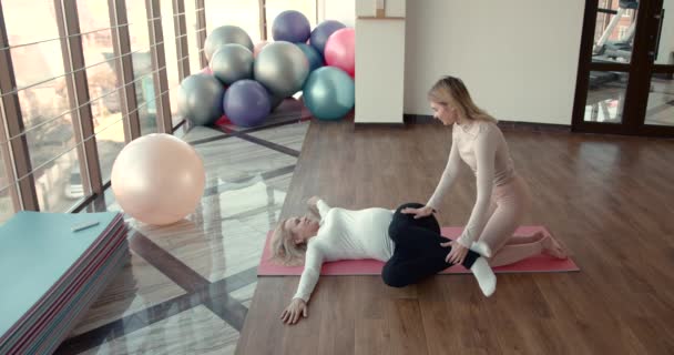Happy trainer helping pregnant woman doing stretching exercises — Stock Video