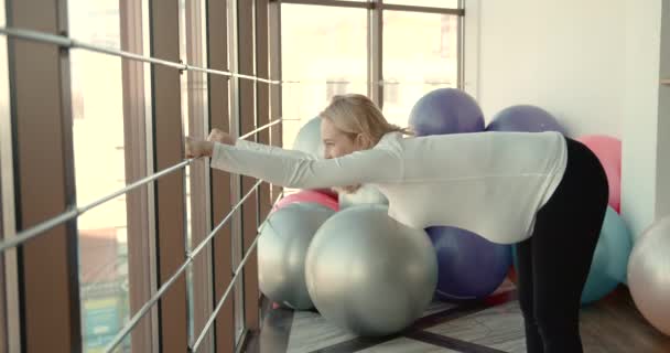 Ciężarna kobieta ćwiczy na siłowni w pobliżu okna — Wideo stockowe