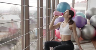 Yorgun kadın spor salonunda spor yaptıktan sonra su içer.