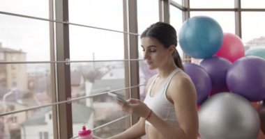 Spor salonunda Smartphone kullanan genç güzel kadın