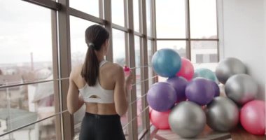 Sportif kız su içiyor ve telefonla konuşuyor.