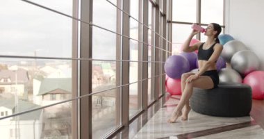 Yorgun kadın spor salonunda spor yaptıktan sonra su içer.