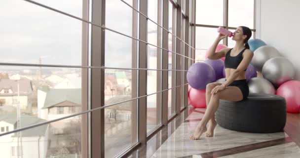 Zmęczona kobieta pije wodę po treningu fitness na siłowni — Wideo stockowe
