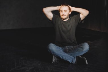 Çaresiz genç uyuşturucu bağımlısı karanlıkta tek başına oturuyor.