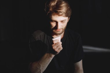 Kokain paketiyle yalnız oturan genç bağımlı adam.