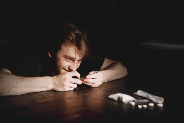 Keş adam şırıngaya uzanıyor.