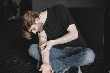 Uyuşturucu bağımlısı koluna eroin enjekte ediyor.