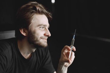 Uyuşturucu için şırınga tutan keş bir adam.