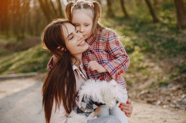 Anne ve kızı bir bahar ormanında köpekle