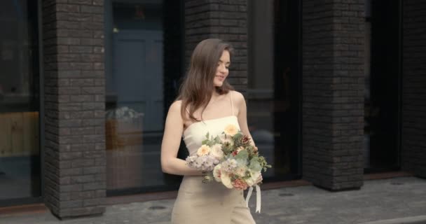 Счастливая элегантная молодая женщина с цветами в городе — стоковое видео