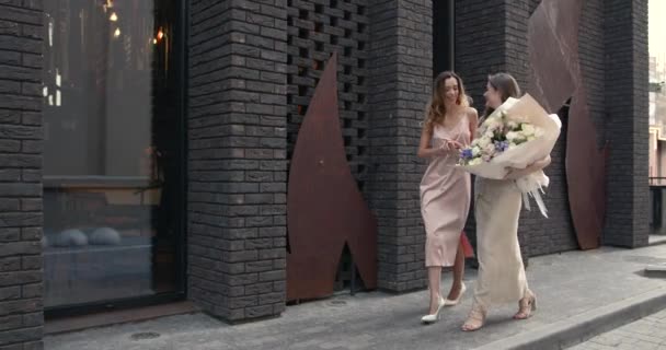 Элегантные женщины с букетами позируют в городе — стоковое видео
