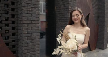 Şehirde çiçekleri olan mutlu, zarif genç bir kadın.
