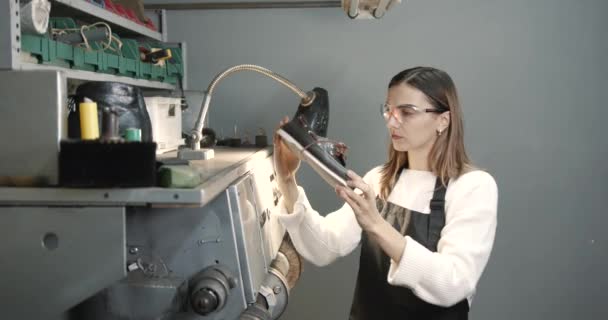 Female shoemaker polishing shoe in a workshop — Stockvideo