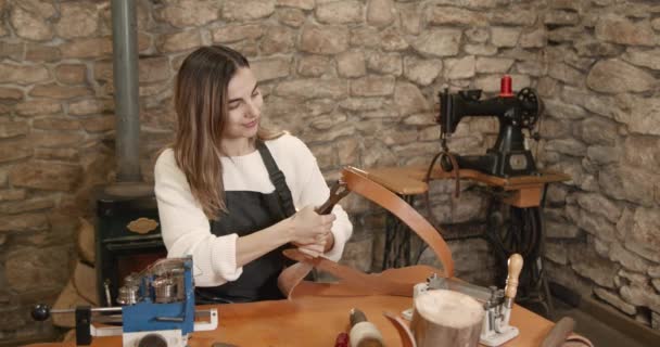 Young woman craftsperson making a leather belt — Vídeos de Stock