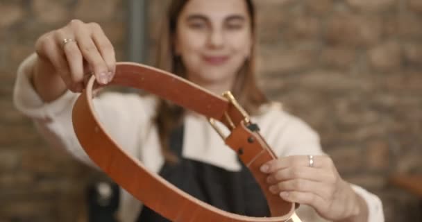 Young woman craftsperson making a leather belt — Wideo stockowe