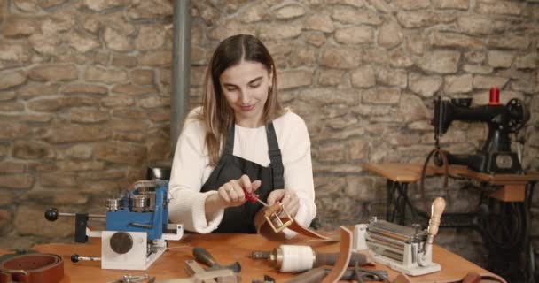 Young woman craftsperson making a leather belt — Vídeos de Stock