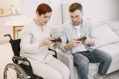 Kıdemli engelli kadın oğluyla video oyunu oynuyor.