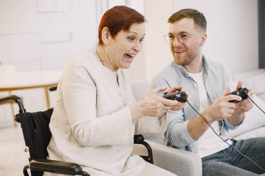 Kıdemli engelli kadın oğluyla video oyunu oynuyor.