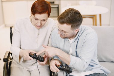 Kıdemli engelli kadın oğluyla video oyunu oynuyor.