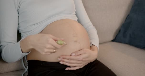 Κοντινό πλάνο της εγκύου γυναίκα μασάζ κοιλιά με έναν κύλινδρο — Αρχείο Βίντεο