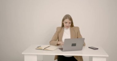 Genç iş kadını ev ofisinde dizüstü bilgisayarla çalışıyor.