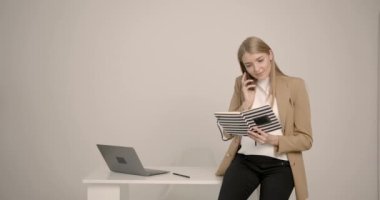 Genç ve şık hamile kadın ofiste oturmuş kitap okuyor.