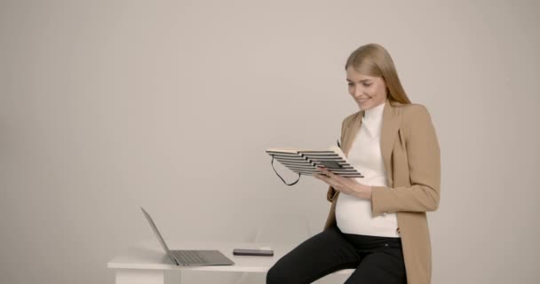 Stilvolle junge schwangere Frau beim Lesen im Büro — Stockvideo