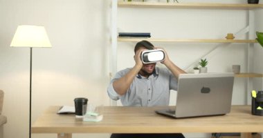 Genç siyah adam evde VR gözlük takıyor.