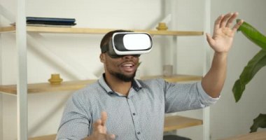 Genç siyahi adam ofiste sanal gerçeklik gözlüğü takıyor.
