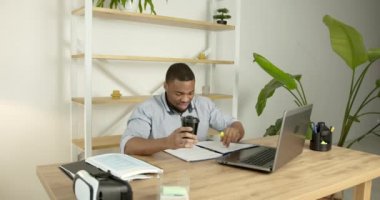 Genç siyah bir adam dizüstü bilgisayarın önünde oturuyor.