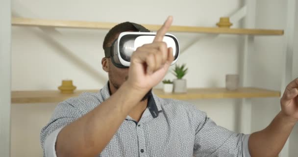 Young black man wears VR glasses at home — Stock videók