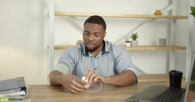 Genç siyahi adam ofiste kan basıncını ölçer.