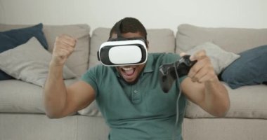 Sanal gerçeklik gözlüklü siyah adam halıda oturuyor.