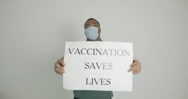 Anti-koronavirüs aşısını destekleyen posterleri olan siyah bir genç adam.