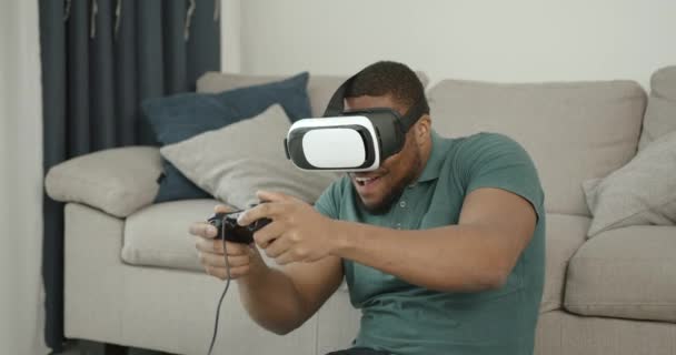 Black man in virtual reality glasses sitting on the carpet — Vídeo de Stock