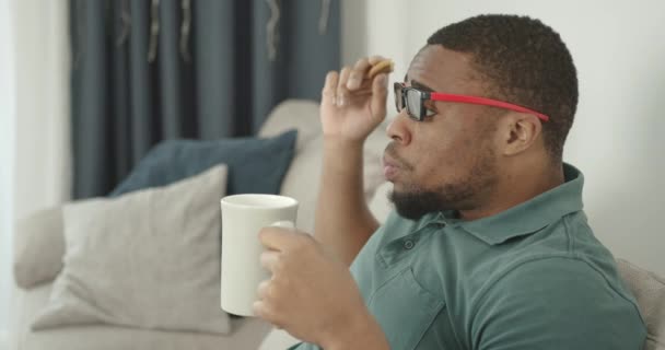 A black young man in 3D glasses watching TV — ストック動画