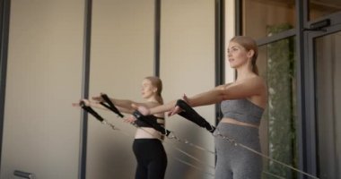 İki sağlıklı hamile kadın pilates makinesinde çalışıyor.