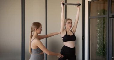 Eğitmenle pilates yapan hamile bir kadın.