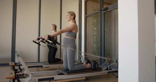 Two fit pregnant woman work on Pilates machines — Vídeo de stock