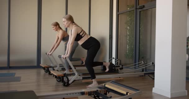 Two fit pregnant woman work on Pilates machines — Video