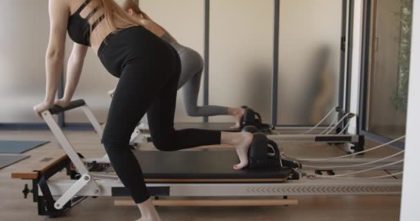 Two fit pregnant woman work on Pilates machines — Stock Video