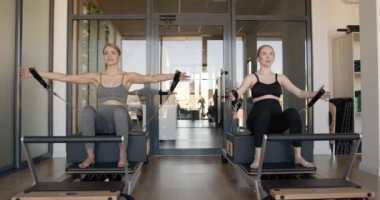 İki sağlıklı hamile kadın pilates makinesinde çalışıyor.