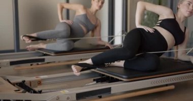 İki sağlıklı hamile kadın pilates makinesinde çalışıyor.