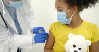 Erkek çocuk doktoru siyahi bir çocuğa aşı yapıyor.